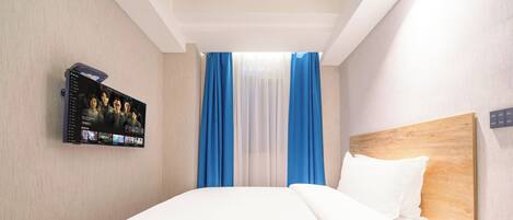 Une chambre d’hôtel avec un grand lit, un téléviseur fixé au mur et une tête de lit en bois.