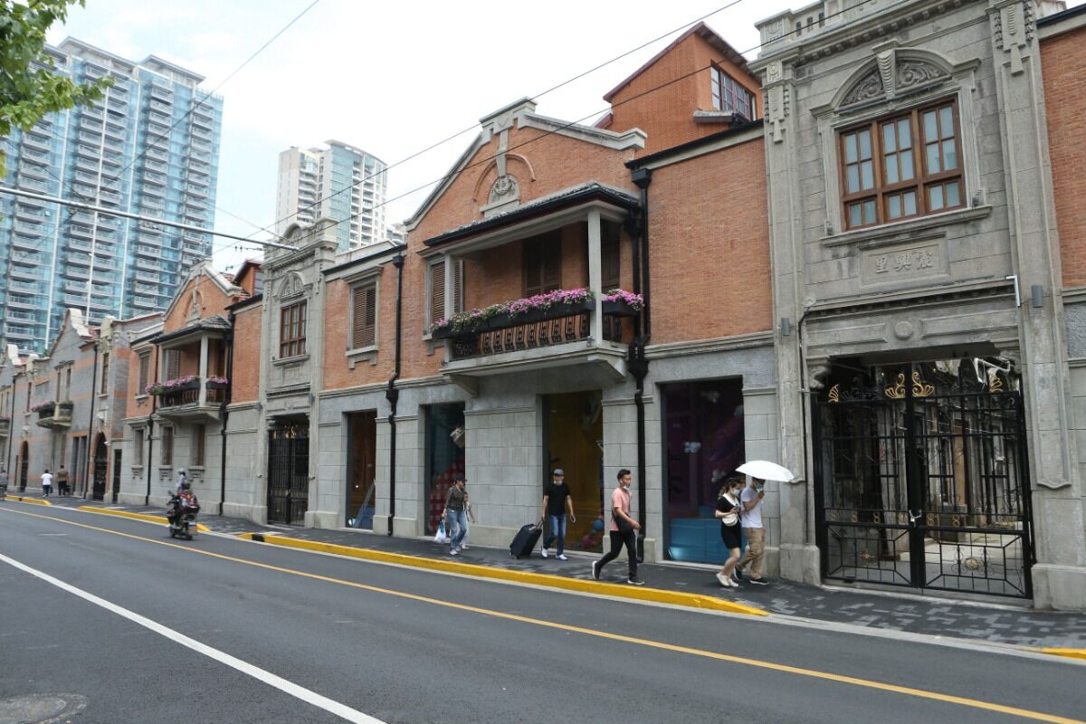 A row of historic buildings with traditional architecture, including balconies with flower boxes and a gated entrance.