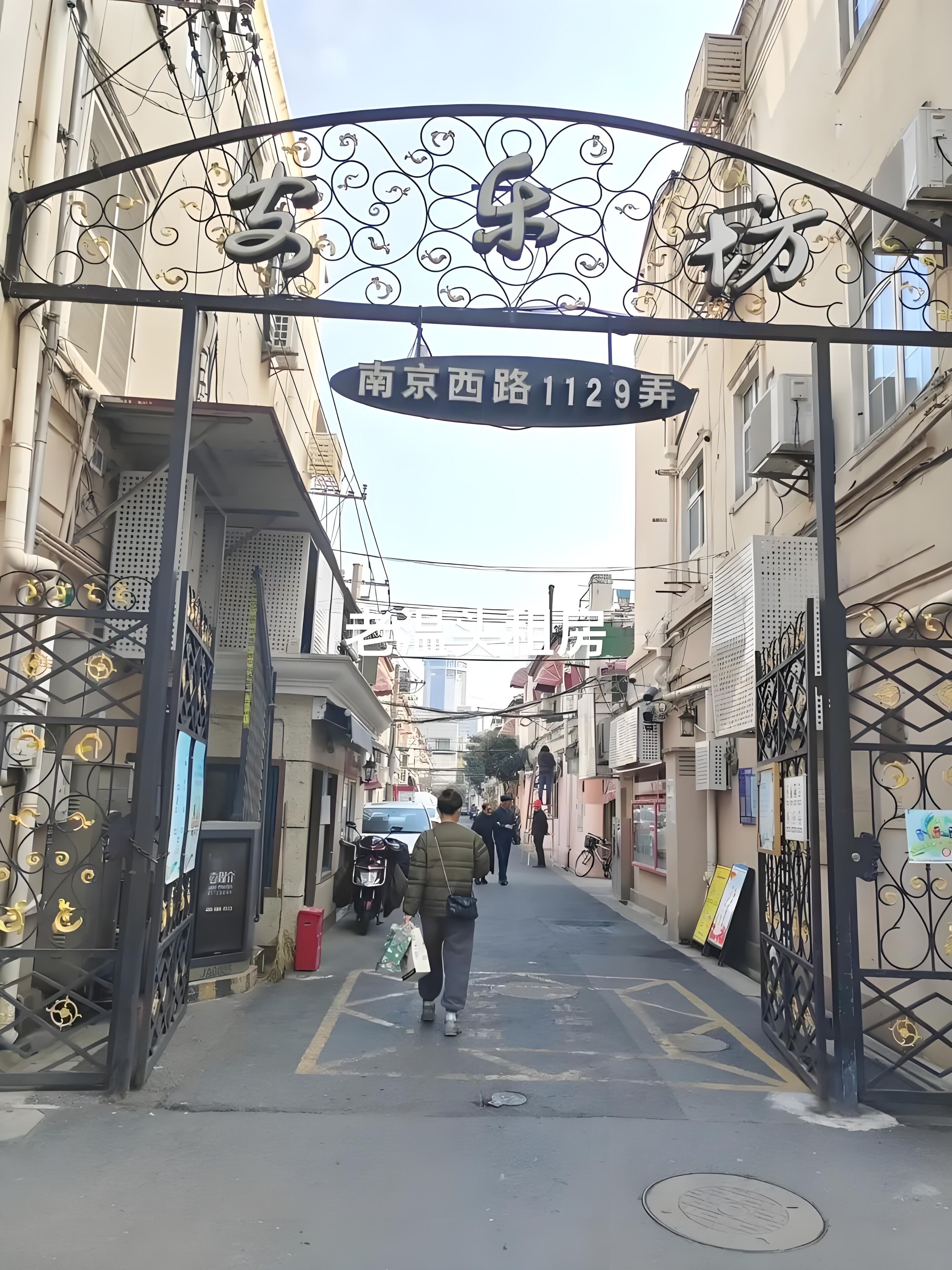 A narrow alleyway with a metal gate and a sign indicating address 1129.