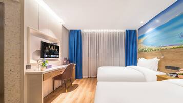 A hotel room with a bed, a desk with a computer, a chair, and a large window with curtains.