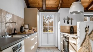 A modern kitchen with a wooden ceiling, a large window, and a hanging pendant light. - "Klint" - 400m from the sea by Interhome (Hals)