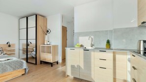 Ein modernes Schlafzimmer mit Bett, Kleiderschrank und Nachttisch. Der Raum verfügt über Holzboden und weiße Wände.
