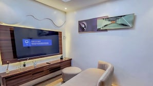 A modern living room with a flat-screen TV, a sofa, a coffee table, and a decorative wall piece. - Tafetta Boutique Hotel  (Abuja)