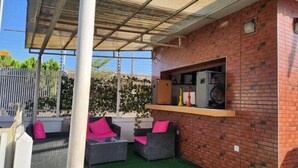 A patio area with wicker furniture, a brick wall, and a glass enclosure. - Tafetta Boutique Hotel  (Abuja)