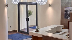 A modern hotel lobby with a reception desk, a blue carpet, and a large mirror. - Icon Hotel  (Luton)
