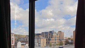 A room with a large window overlooking a cityscape with various buildings and a parking area. - Icon Hotel  (Luton)