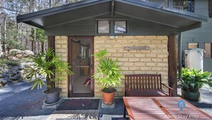 Une maison avec une façade en briques, un banc en bois et des plantes en pot.