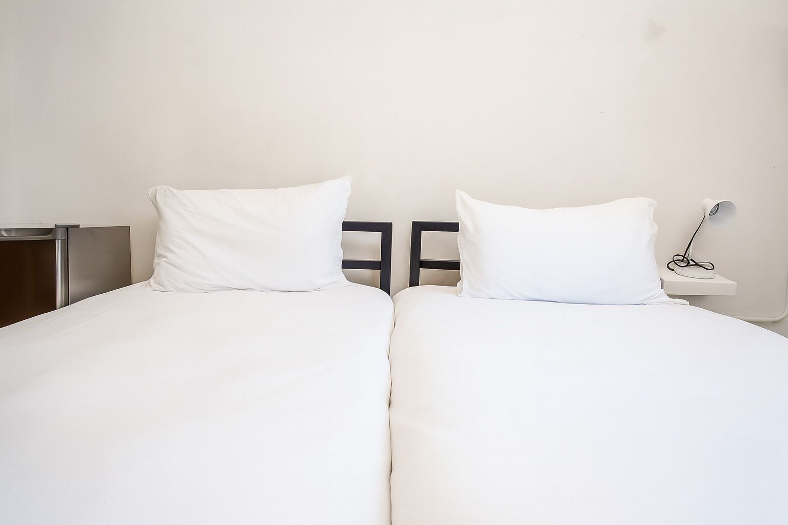 A double bed with white bedding and a nightstand with a lamp.