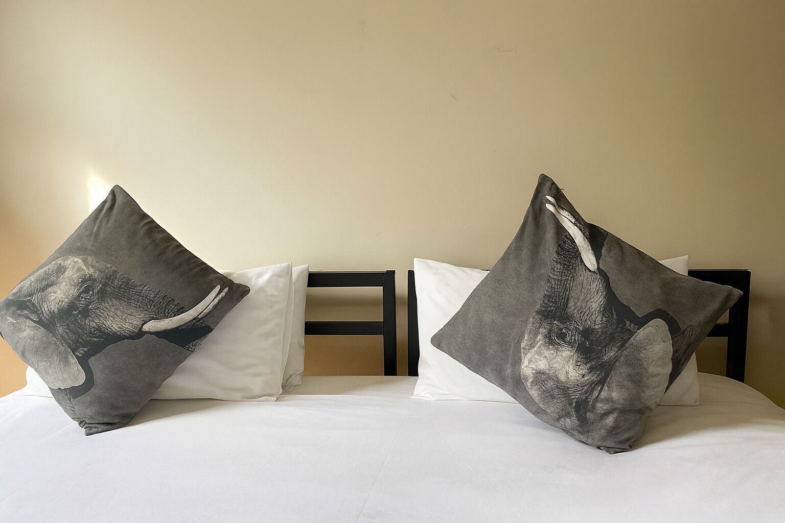Una cama con dos almohadas, una con un elefante y otra con un tiburón.