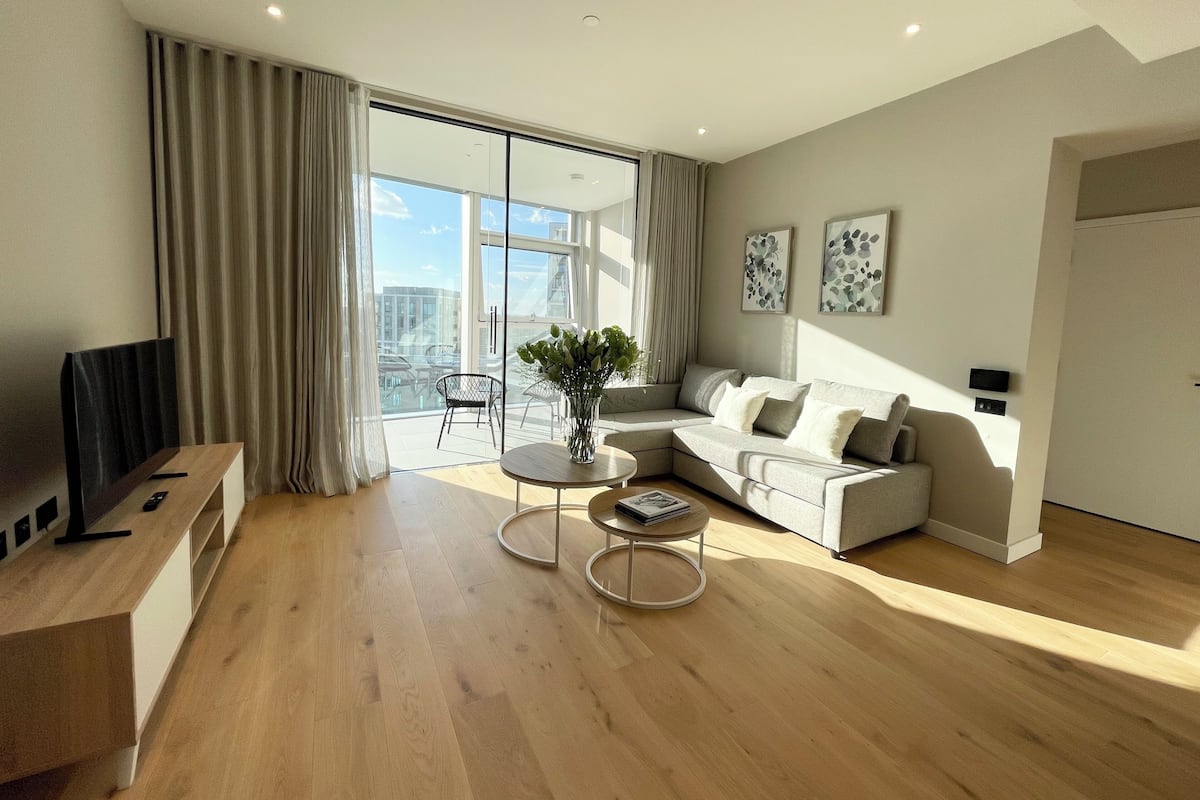 A modern living room with a sofa, coffee table, and a TV stand.