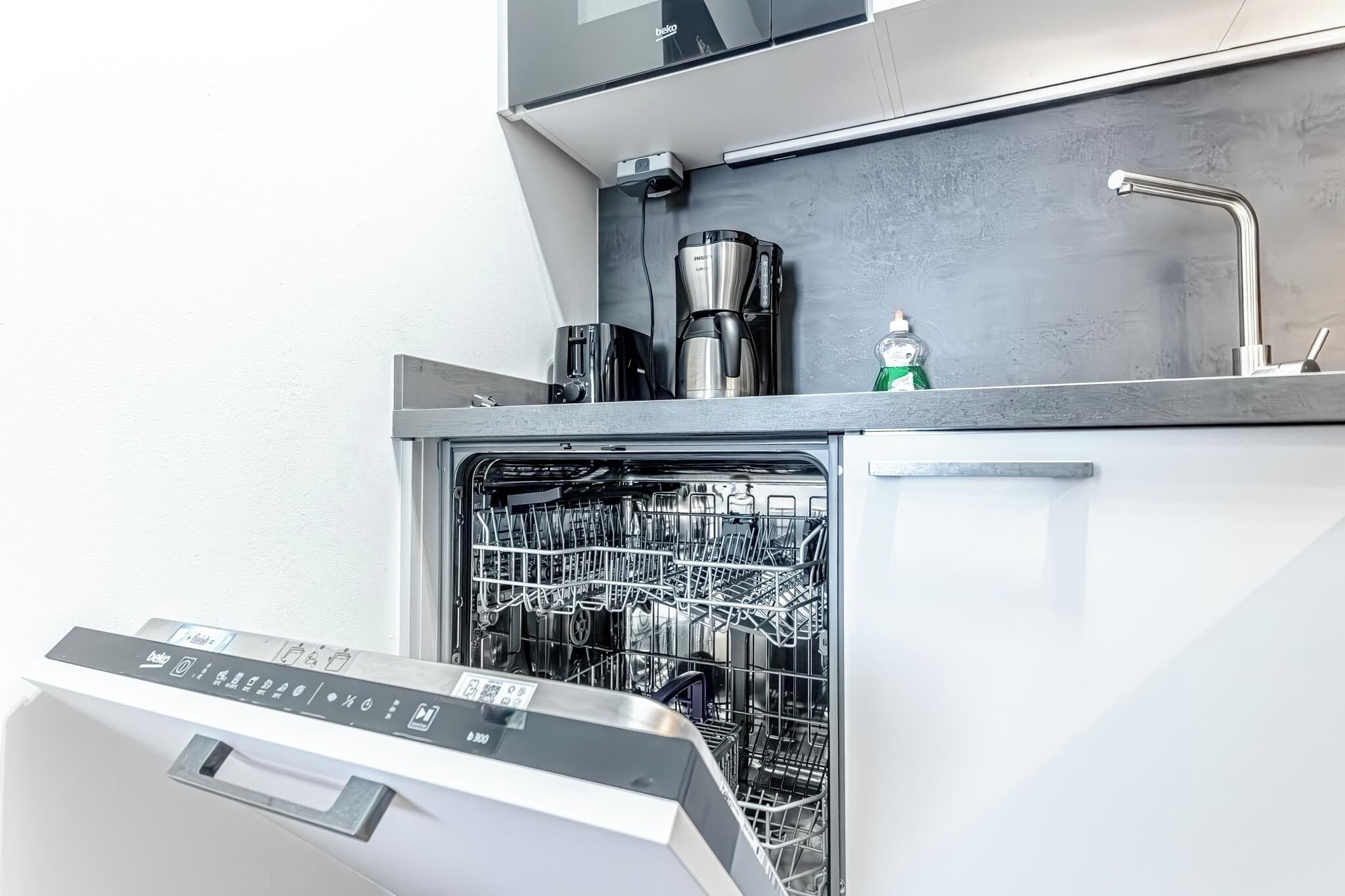 Una cocina moderna con lavavajillas, cafetera y pileta.
