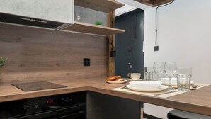 Une cuisine moderne avec des plans de travail en bois, un four encastré et un coin repas avec une table dressée pour quatre personnes.