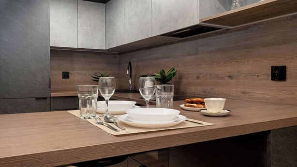 Une cuisine moderne avec un plan de travail en bois, des armoires grises et une cuisinière intégrée.
