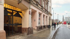 Un immeuble doté d’une entrée sécurisée par un portail, d’un trottoir carrelé et situé dans une rue où circule un tramway.