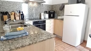 Een moderne keuken met granieten aanrechtbladen, roestvrijstalen apparatuur en houten kastjes.