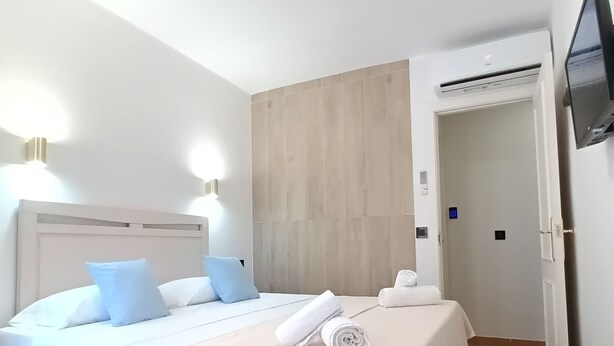 Een hotelkamer met een bed, een televisie en een deur.