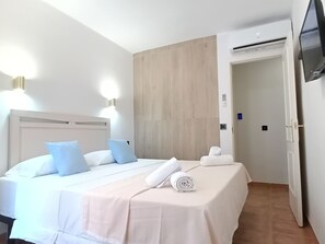 Quarto de hotel com uma cama, televisão e porta.