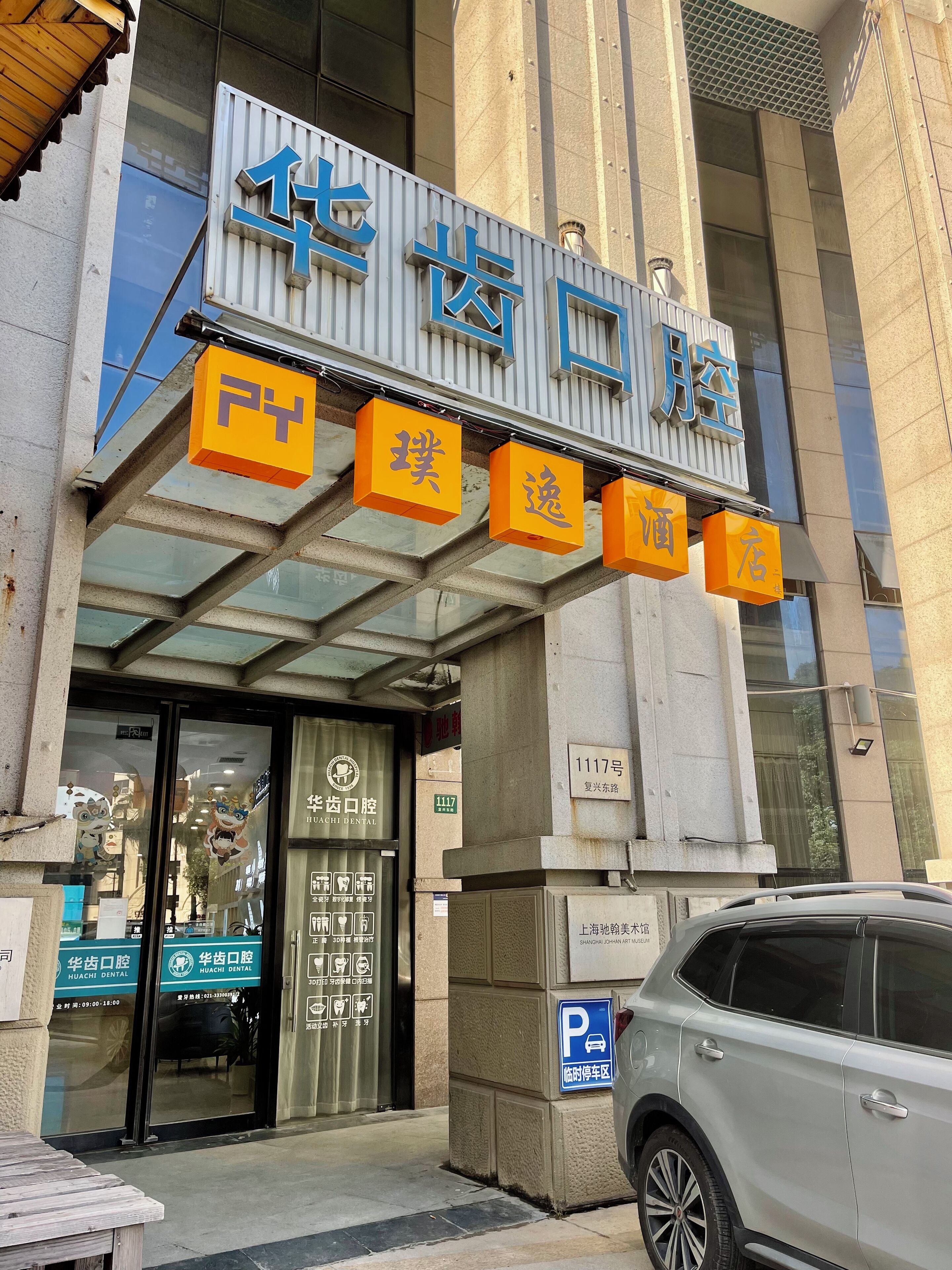 A building with a sign for "Huachi Dental" and a parking sign.