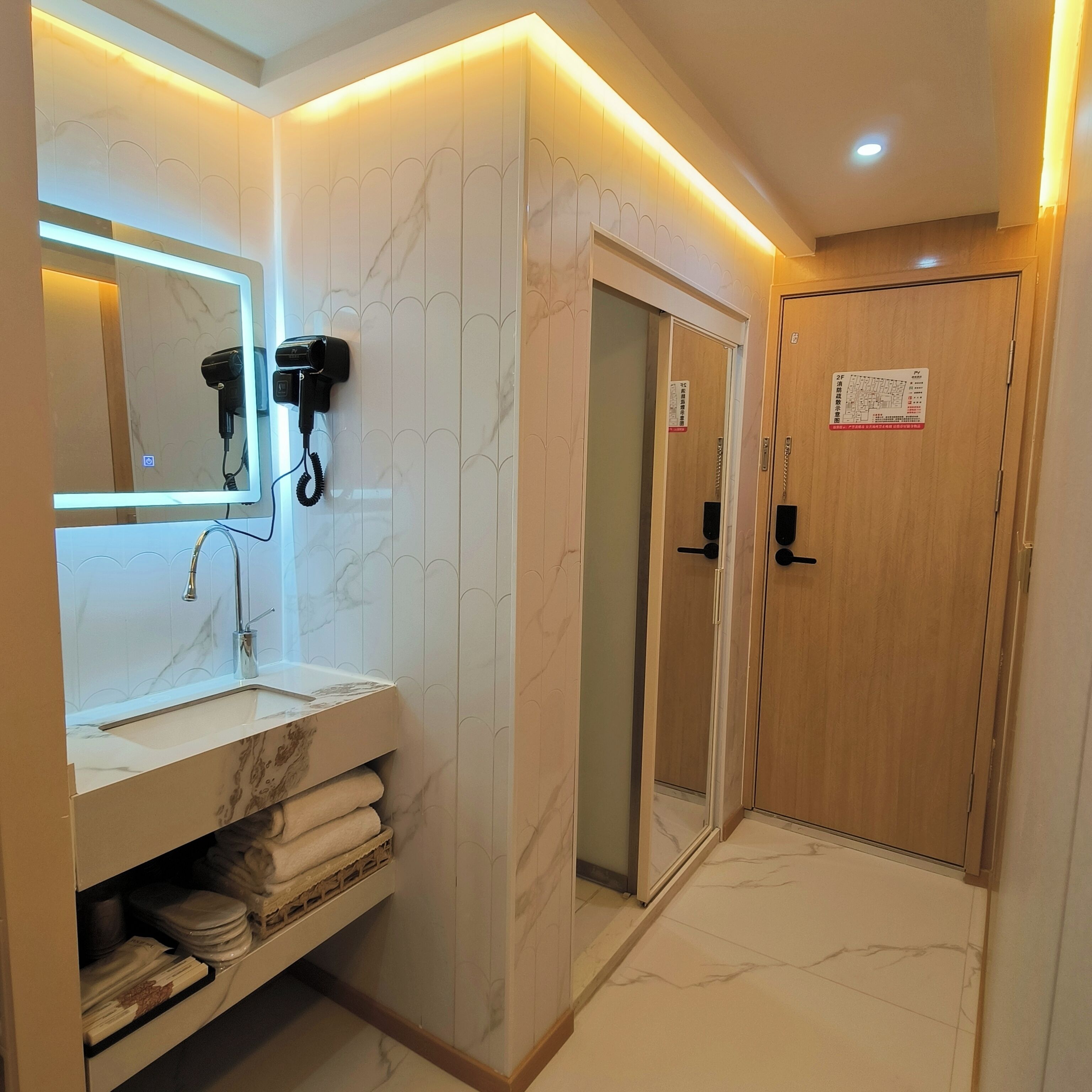 A modern bathroom with a marble vanity, a hairdryer, and a shower area.