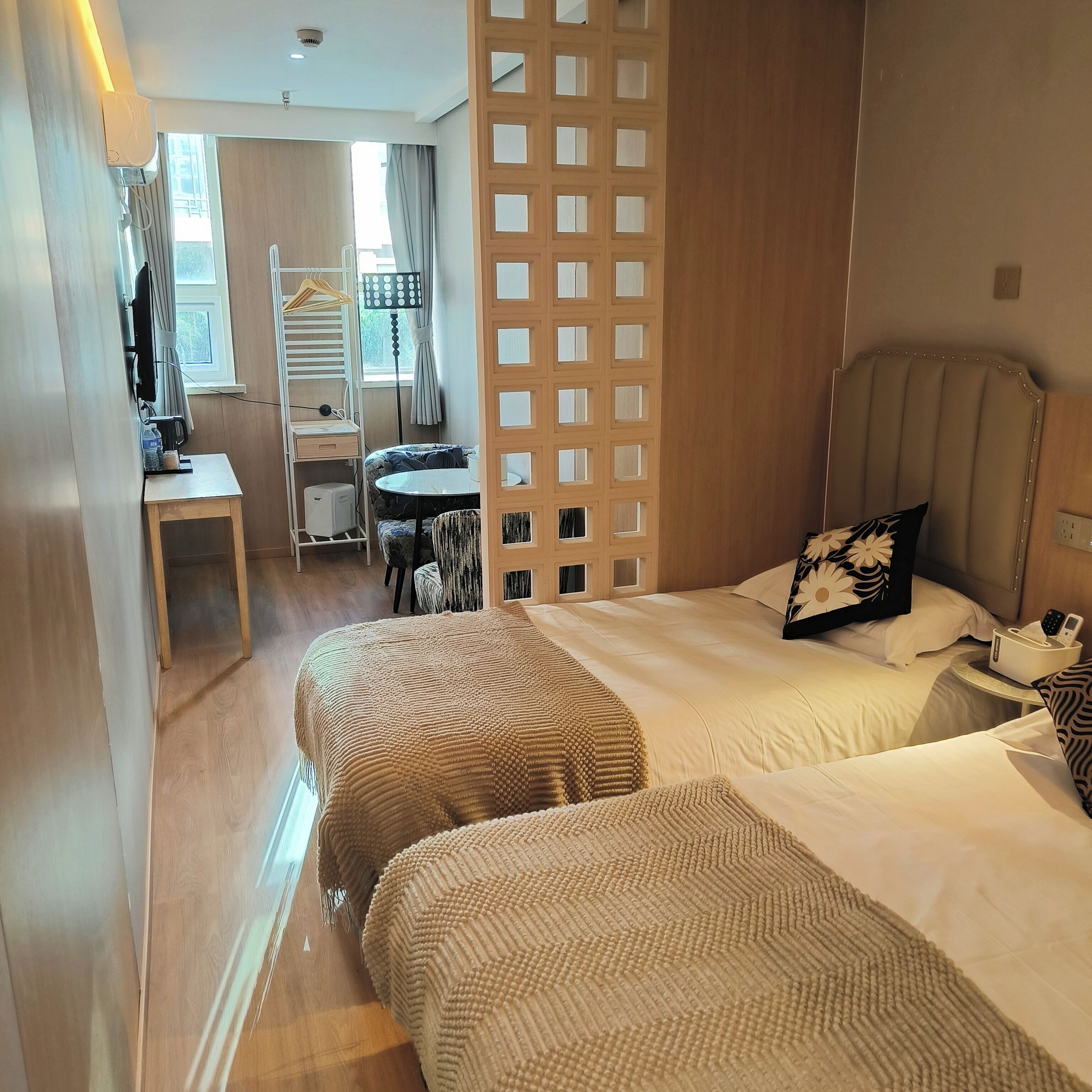 A hotel room with two beds, a desk, a chair, and a small table.