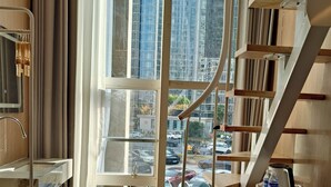 Une chambre moderne dotée d’une grande fenêtre, de planchers en bois et d’une bibliothèque intégrée.