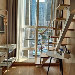 A modern room with a large window, wooden floors, and a built-in bookshelf. - Shanghai Puyi Hotel (Shanghai)