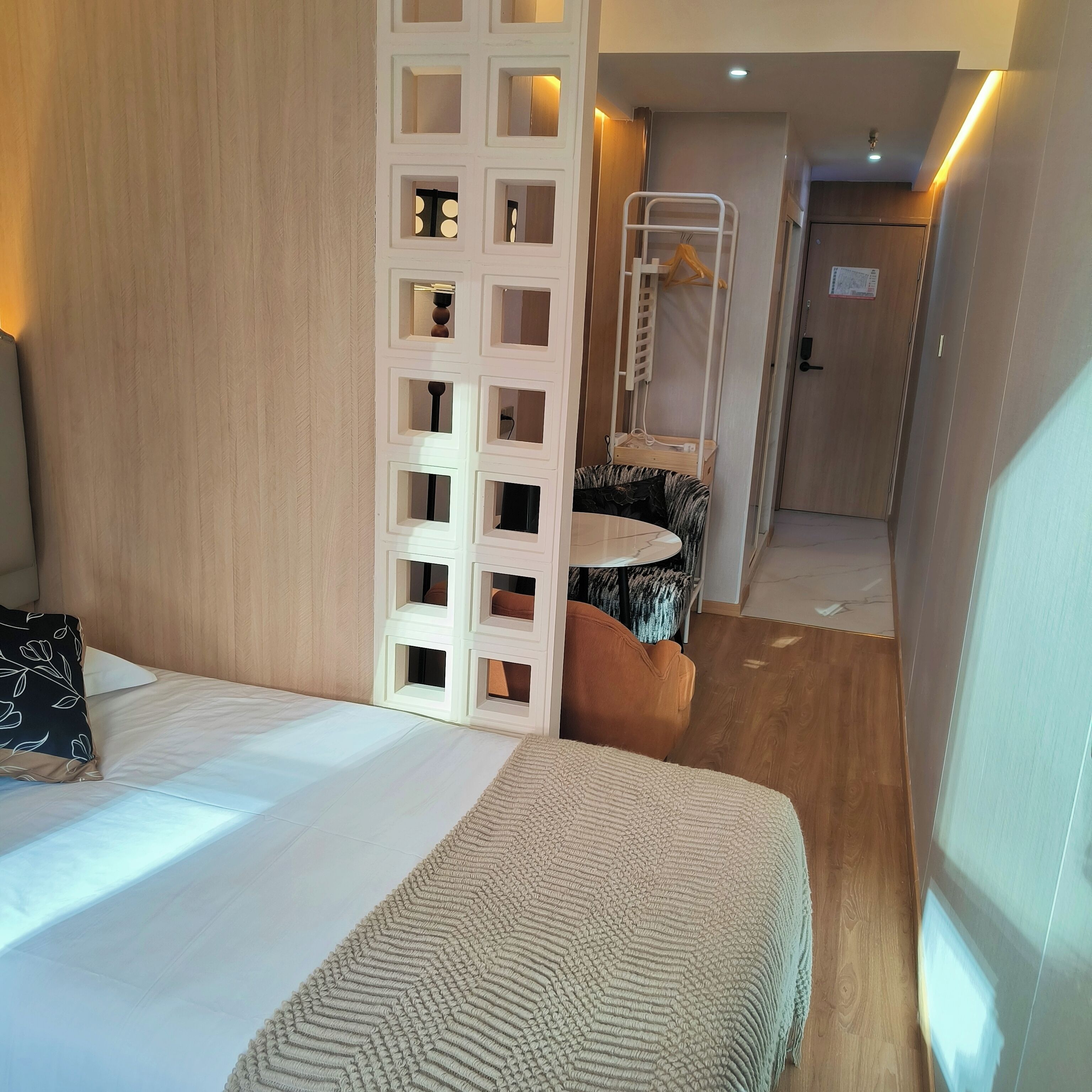 A hotel room with a bed, a small round table, a chair, and a wardrobe.