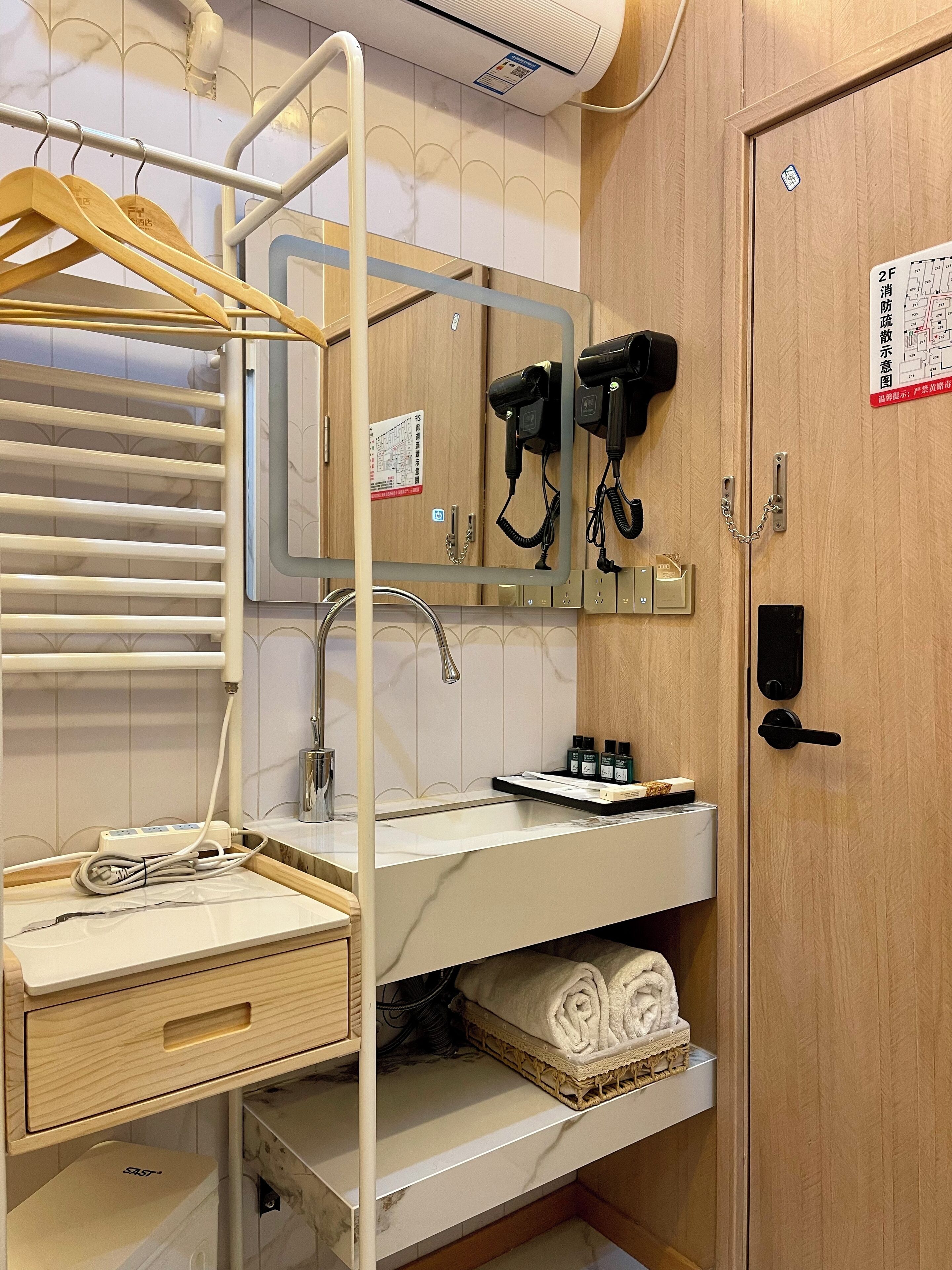 A bathroom with a wooden vanity, a towel rack, a mirror, a hairdryer, and a map on the wall.