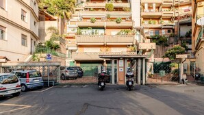 Een meerlaags gebouw met een hek en parkeerplaats voor auto's en motorfietsen.