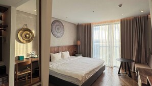 Moderni hotellihuone, jossa on suuri sänky, työpöytä, tuoli ja peili.