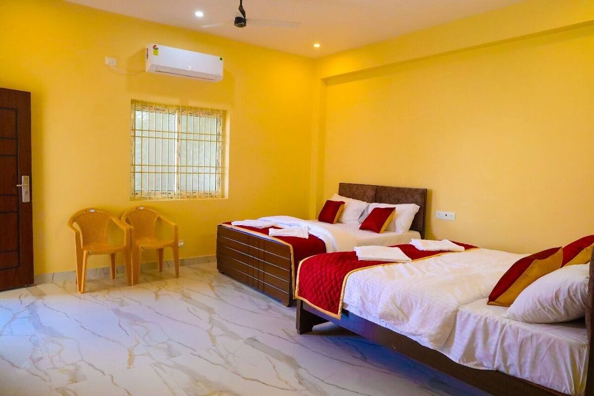 A hotel room with two beds, a window with bars, a ceiling fan, and an air conditioning unit.
