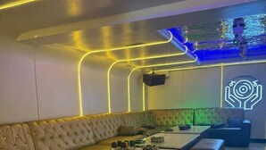 A modern lounge with a sofa, a coffee table, and a neon light design on the ceiling. - Sanso Hotel (Kampala)