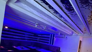 A modern interior with a sloped ceiling, seating area with tables and chairs, and a patterned wall. - Sanso Hotel (Kampala)