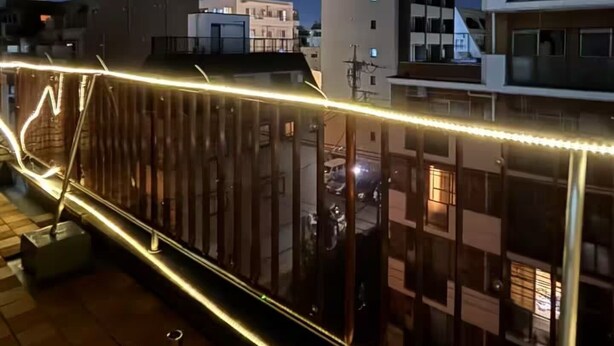 Vista nocturna de un paisaje urbano con una torre iluminada al fondo.