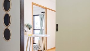 Una habitación con puerta corredera, una mesita con un florero y un espejo en la pared.