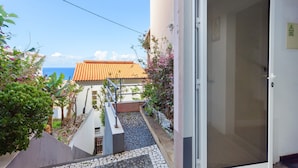 Un bâtiment situé sur la côte, doté d’un toit recouvert de tuiles, d’un escalier menant à une porte et offrant une vue sur la mer.