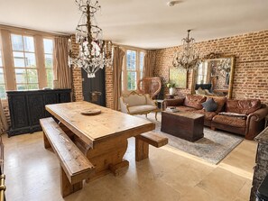 A spacious living room with a large wooden table, a leather sofa, and a chandelier. - Knightsbridge 2BR Mews House (London)
