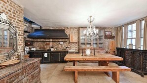 Eine rustikale Küche mit Backsteinwand, Holztisch, Bank und einer Pendelleuchte.