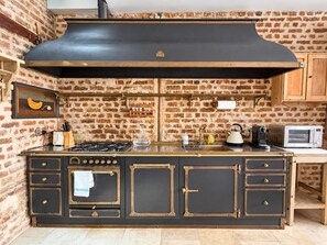 Una cocina con pared de ladrillo, estufa negra grande y armarios de madera.
