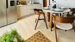 Una cocina moderna con un refrigerador de acero inoxidable, armarios de madera y una zona de comedor con una mesa redonda y sillas.