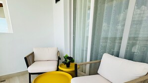 Una sala de estar moderna con dos sillones, una mesita de centro amarilla y un ventanal con cortinas.