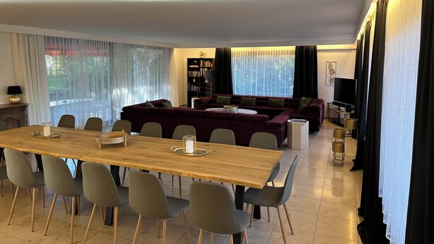 A modern living room with a wooden dining table, grey chairs, a dark red sofa, and a bookshelf. - House Anna Alpirsbach (Alpirsbach)