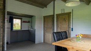 Et køkken med et vindue, et spisebord med stole og et træloft.