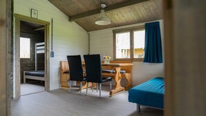 Et hyggeligt kabine-værelse med køjeseng, et træskrivebord med stole og en enkeltseng.