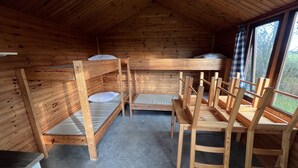 A wooden cabin interior with bunk beds and a dining table.