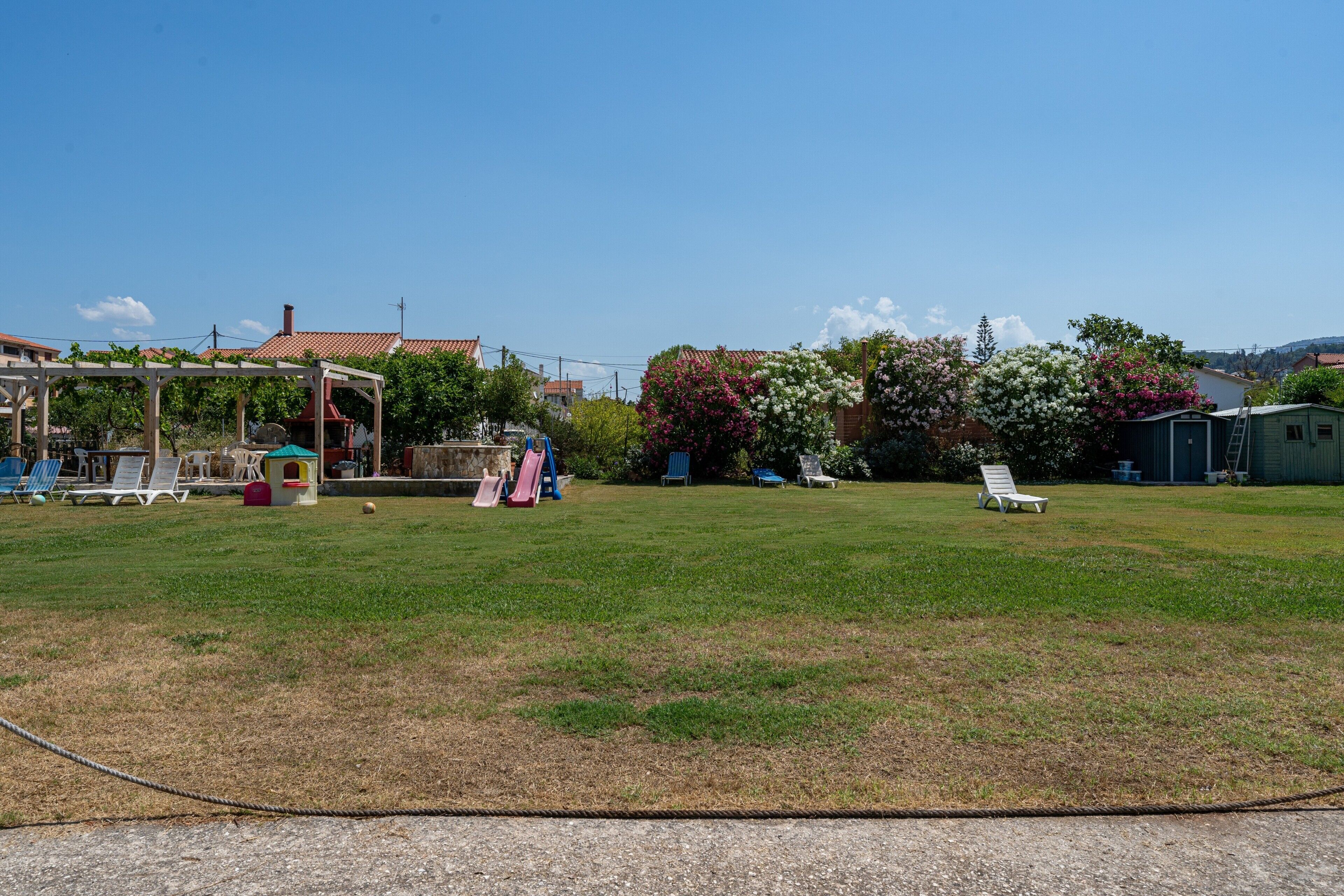 Un'area verde con un set giochi per bambini, un gazebo e un piccolo deposito.