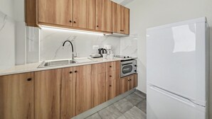 Eine Küche mit Holzausstattung, einem weißen Kühlschrank, einer Spüle und einer Mikrowelle.