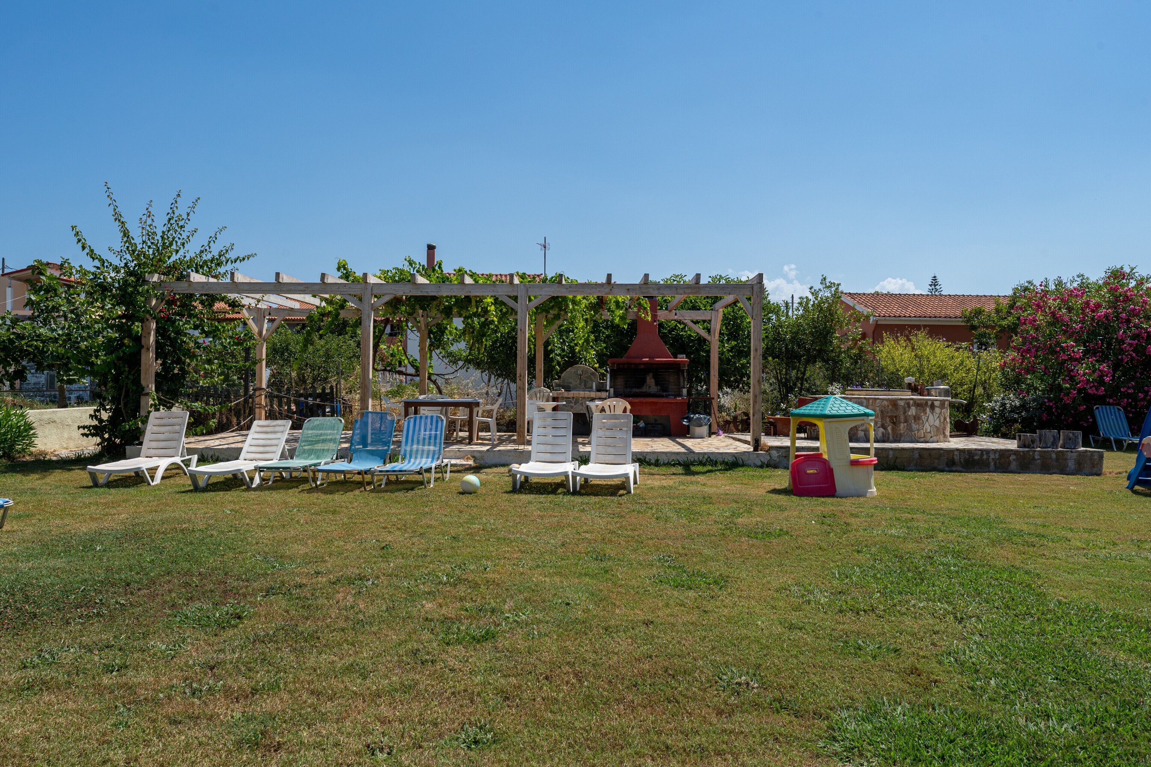 A garden with outdoor seating, a pergola, and a small playhouse.
