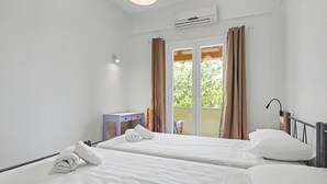 Una camera d'albergo con due letti, una piccola scrivania, un condizionatore d'aria e una porta scorrevole in vetro che dà sull'esterno.