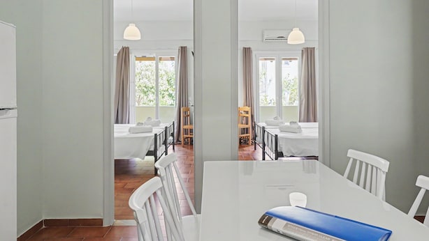 Zona pranzo con tavolo bianco, sedie e menù blu.